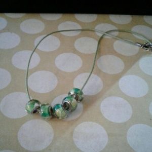 5 green toned euro beads on a green cord